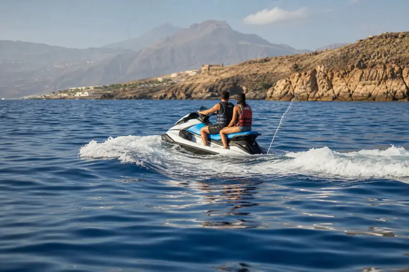 Pilote et passager équipés de gilets sur une moto nautique au large de la côte sud de Tenerife.