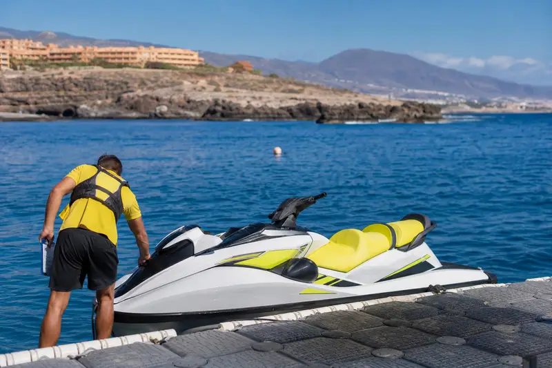 Contrat de location et gilet de sauvetage posés près d’un jet ski dans la marina de Puerto Colón à Tenerife.