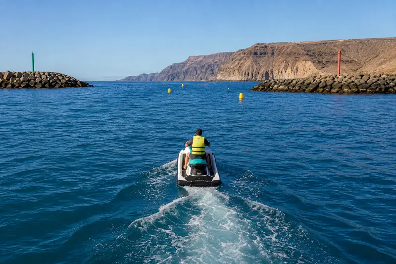 Groupe de jet skis naviguant lentement dans un chenal balisé au départ de Costa Adeje à Tenerife.