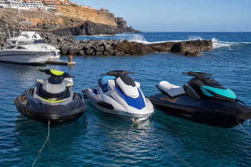 Trois motos nautiques modernes amarrées dans une marina de Costa Adeje à Tenerife, prêtes pour une sortie matinale.