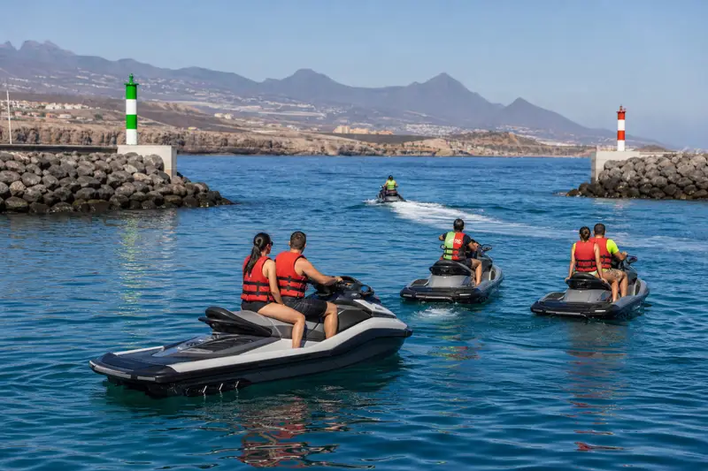 Jet ski naviguant le matin au large de Tenerife avec les falaises de Los Gigantes en arrière-plan.