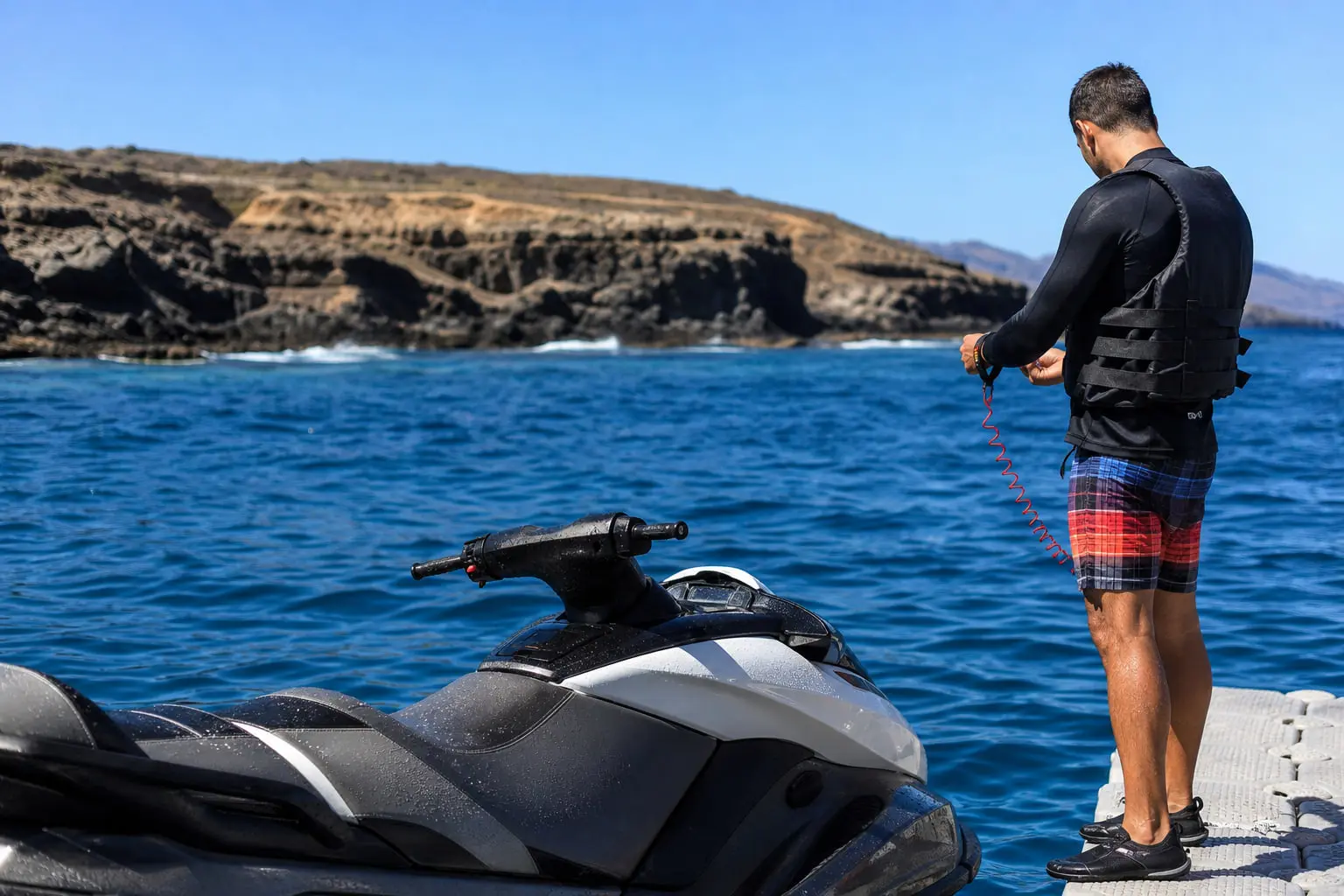 Pilote équipé d’un haut anti-UV, d’un gilet de sauvetage et de chaussures d’eau avant une sortie en jet ski à Costa Adeje, à Tenerife.